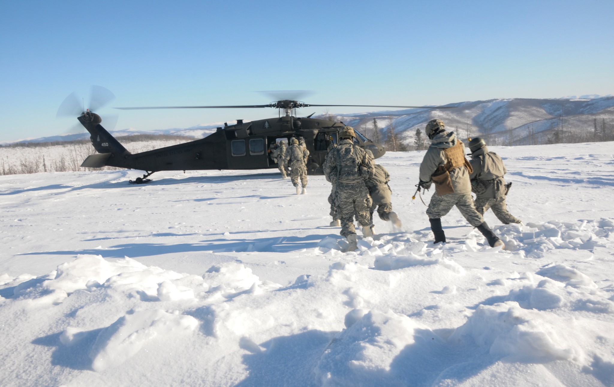 Members of 1st Battalion, 297th Infantry Regiment based in Fairbanks, Alaska and part of the Alaska National Guard prepare to board a UH-60 Black Hawk Helicopter operated by members of 1st Battalion, 169th Aviation Regiment of the New Hampshire National Guard Feb. 28, in the Yukon Training Area on Eielson Air Force Base as part of exercise Arctic Eagle 2020.